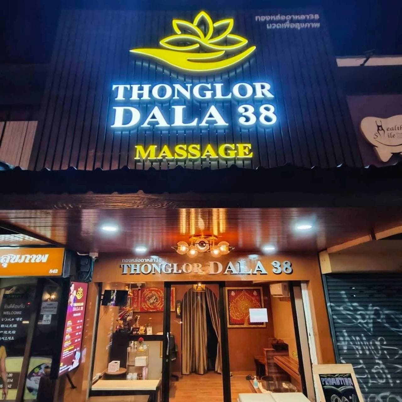 Entrance of THONGLOR DALA38 massage shop beneath its illuminated storefront sign